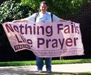 Protesting outside "Public Square Rosary Crusade" event holding FFRF "Nothing Fails Like Prayer" banner